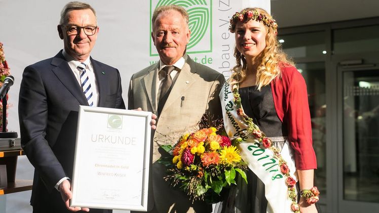 Im Rahmen des Deutschen Gartenbautages 2018 verlieh ZVG-Präsident Mertz Winfried Kaiser die Ehrennadel in Gold für sein außerordentliches Engagement zum Wohle des Deutschen Gartenbaus. (v. l. n. r.: Mertz, Kaiser und Deutsche Blumenfee 2017/18). Foto ZVG/ Thomas Rafalzyk.