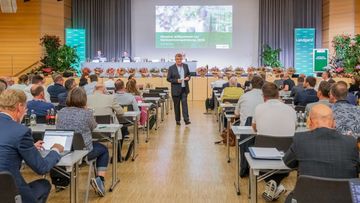 Bert Schmitz (im Vordergrund, Aufsichtsratsvorsitzender Landgard eG), auf dem Podium dahinter v. l. Christoph Klöpper und Moritz Krannich (beide Vorstand Landgard eG) und Dirk Schwichtenberg (stellv. Aufsichtsratsvorsitzender). Bild: Landgard.