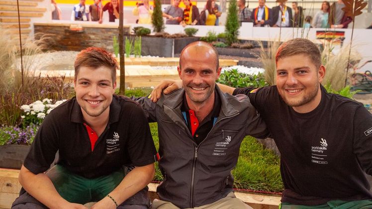 Julian Maier (links) und Niklas Stadlmayr (rechts) – hier mit Trainer und Experte Johannes Gaugel (Mitte) – sicherten sich den 9. Platz im Wettbewerb „Landscape Gardening“ bei den WorldSkills 2019 Kazan in Russland. Bild: AuGaLa.