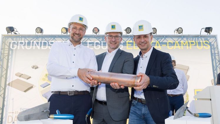 Mark Rosenkranz, Stephan Wohler und Ulf-U. Plath (v.l.n.r.) lassen gemeinsam die EDEKA-Zeitkapsel in die gemauerte Vorrichtung ein, auf die im Anschluss der Grundstein gelegt wird. Bild: EDEKA/ Christian Schwier.