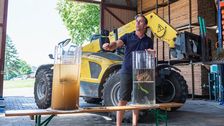 Reto Minder ist Präsident von Swiss No-Till und führt einen Betrieb in Jeuss FR. Auf dem Bild vergleicht er die Reaktion von gepflügtem (l.) und ungepflügtem Boden im Wasser. Bild: Hansjürg Jäger/IFAJ2024.