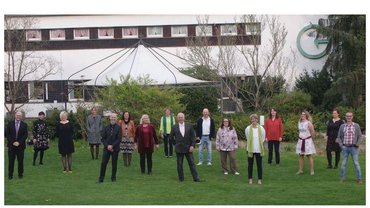 Die 14 Absolventen der Weiterbildung GÄRTEN HELFEN LEBEN zeigen sich mit ihren Zertifikaten und gebührendem Abstand auf der Rasenfläche vor der Bildungsstätte in Grünberg. Bild: M. Hub.