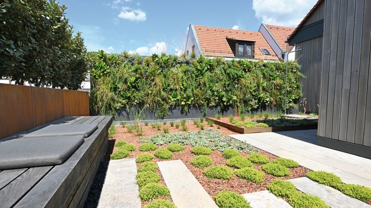 Den Bodenbelag der neu gestalteten Fläche prägen helle, längliche Natursteinplatten, die auch innerhalb der Beete ein Durchschreiten ermöglichen. Sie bilden gewissermaßen zwei Zebrastreifen, die zudem die Pflege der Beetflächen durch eine bessere Zugänglichkeit erleichtern. Foto: Richard Brink GmbH & Co. KG.