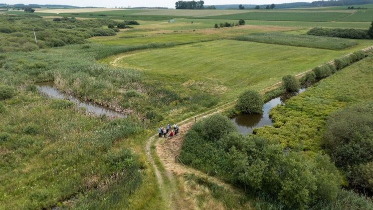 Das Bild zeigt eine Schwammregion mit landwirtschaftlichen Flächen und Wasserläufen. Motto: „Viele kleine Maßnahmen in der Fläche tragen zur Speicherung von Wasser bei.“ Bild: Bewegter Blick/StMELF.