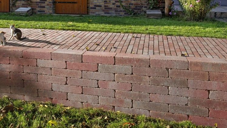 Das puristische Design der Kibo-Mauer bietet einen attraktiven Blickfang bei der Terrassengestaltung. Hinter der Mauer wurde das Kibo-Pflaster in rot im klassischen Läuferverband verlegt. Bild: KANN, Bendorf.