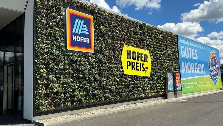 Die HOFER Filiale in der Gatterederstraße 11-15 überzeugt durch ein Photovoltaik-Carport, Außenfassaden- und Dachbegrünung sowie eine Bienenblumenwiese. Fotocredit: © BRIGHT FILMS.