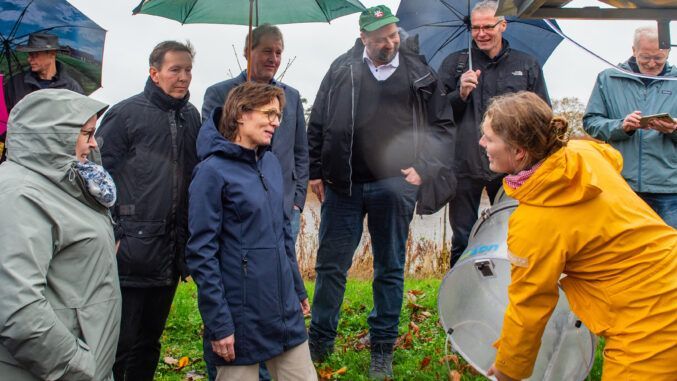 Lena Hauschildt (re.), Mitarbeiterin am Grünlandzentrum Niedersachsen/Bremen, zeigt der Besuchergruppe um Jessika Roswall den Ablauf der Messungen von Emissionen bei unterschiedlichen Wasserständen auf den Versuchsflächen des Projektes „GreenMoor II". Foto: Kluge.