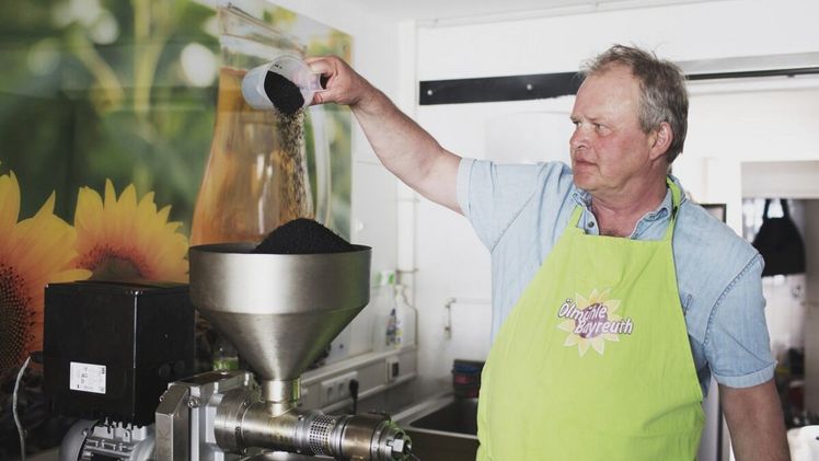Klaus Lünsmann aus der Öko-Modellregion Fränkische Schweiz beim Befüllen der geförderten Ölpresse mit heimischem Bio-Raps. Bild: Daniel Delang/ALE Oberbayern.
